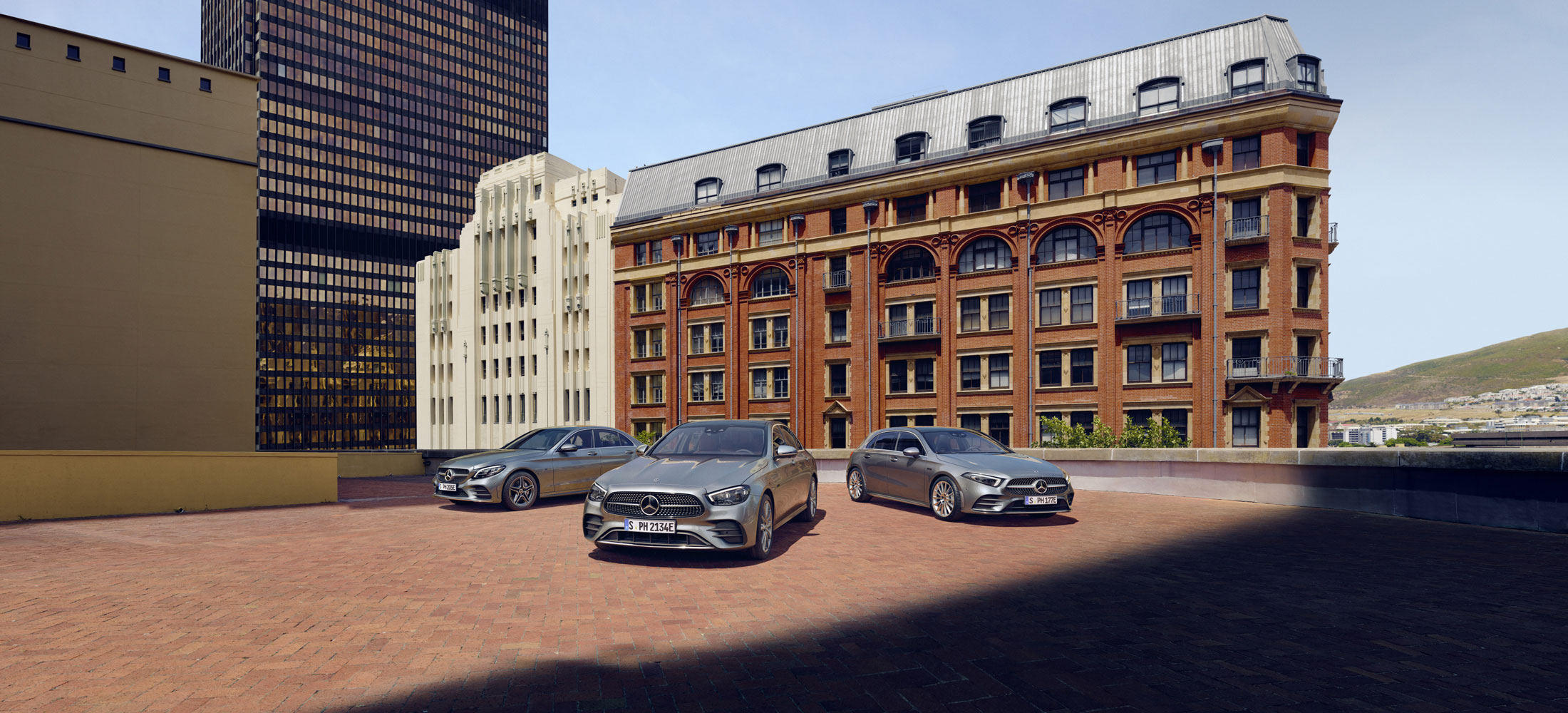 zu sehen sind drei unterschiedliche graue Mercedes-Benz Modelle vor einem großen Gebäude.