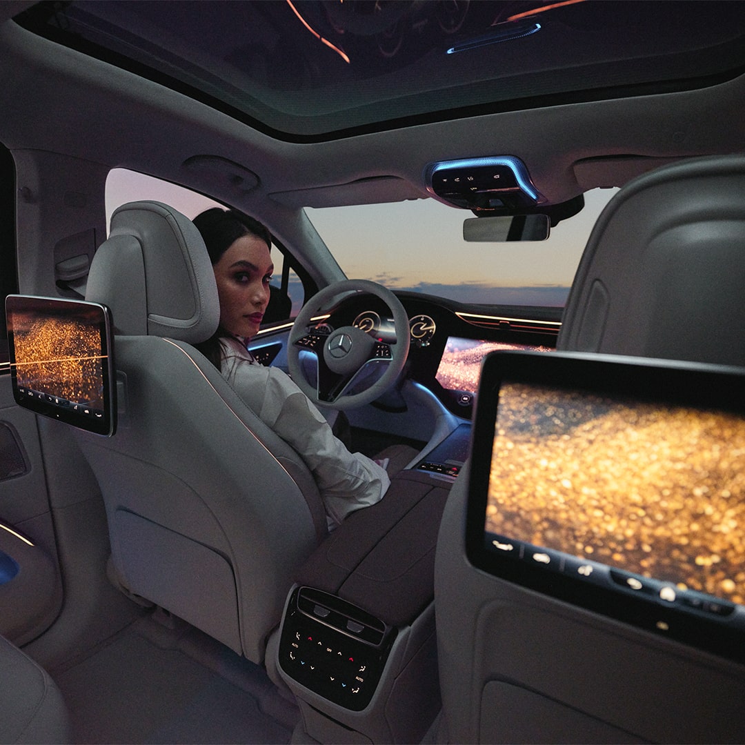 Zu sehen ist eine Frau am Steuer, die in einem Mercedes-Benz Auto sitzt. 