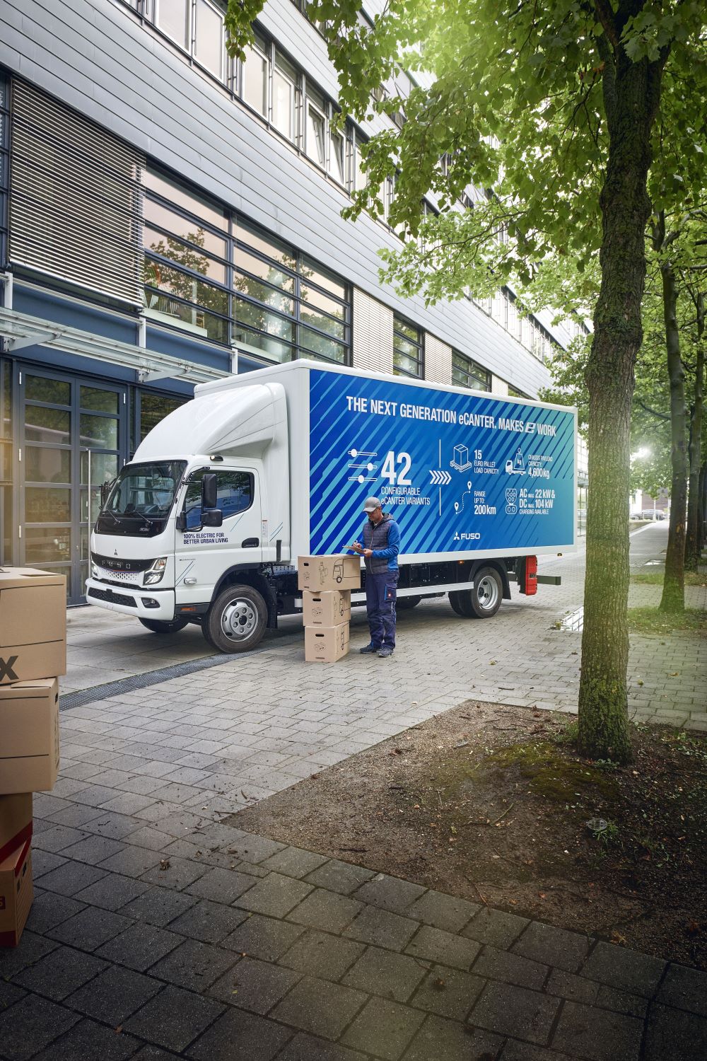 Zu sehen ist ein Mitsubishi LKW. Davor steht ein Mann, der Pakete liefert. 