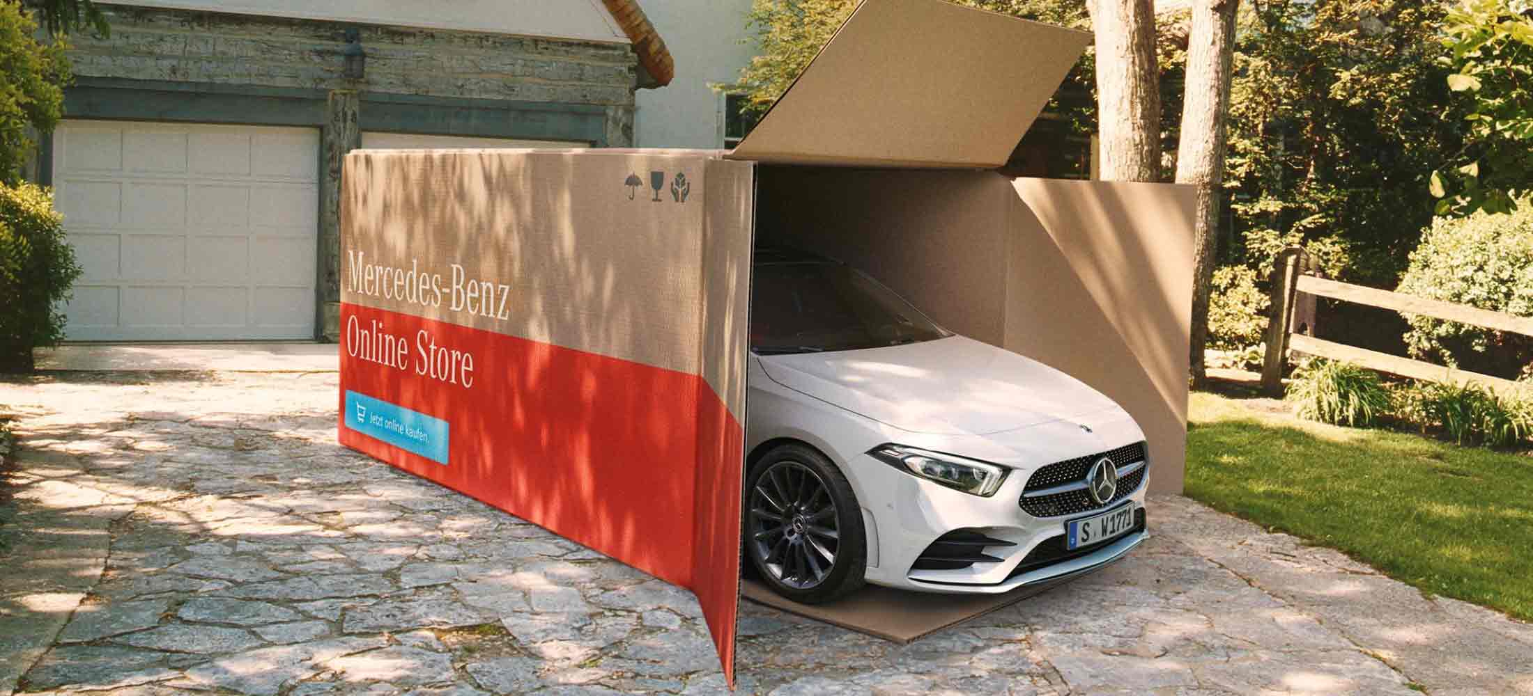 Zu sehen ist ein Mercedes-Benz in einem XXL-Karton mit der Aufschrift Mercedes-Benz online store, jetzt online kaufen.