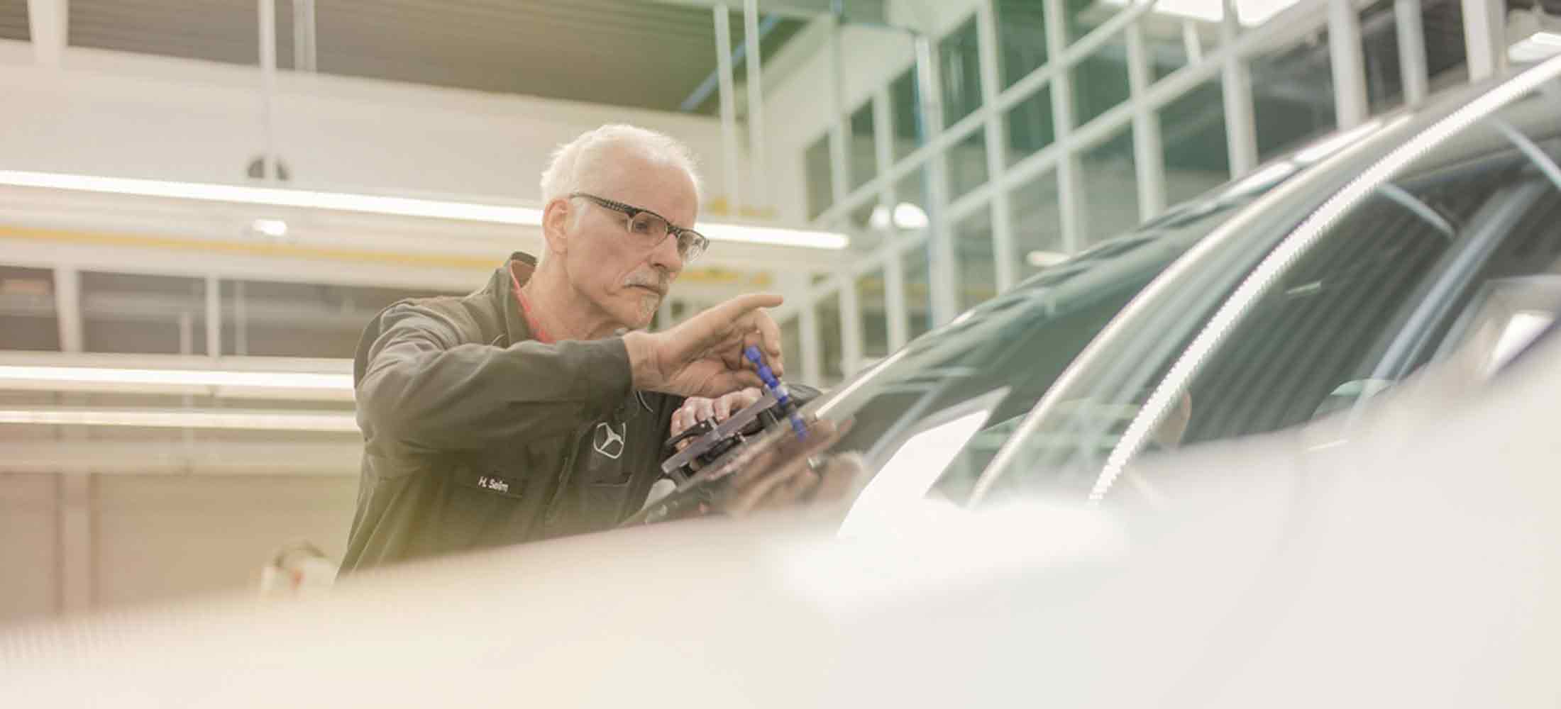 ein Mitarbeiter prüft die Scheibe eines Autos