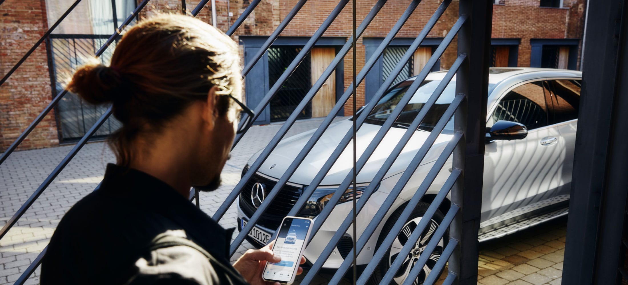 Auf dem Bild: Mann am Handy vor einem Mercedes